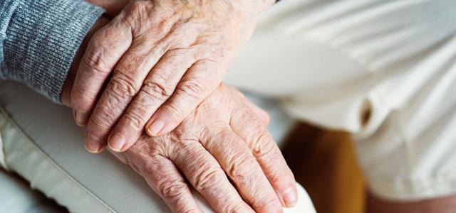 Close up of a retired couple holding hands.